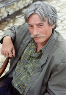 Jean Ferrat assis sur une chaise.